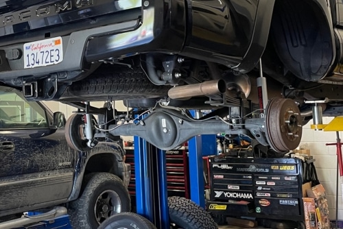 Suspension repair and customization in Martinez, CA at Outlander Motorsports. Image of black toyota tacoma v6 being lifted for superior suspension repair and customization