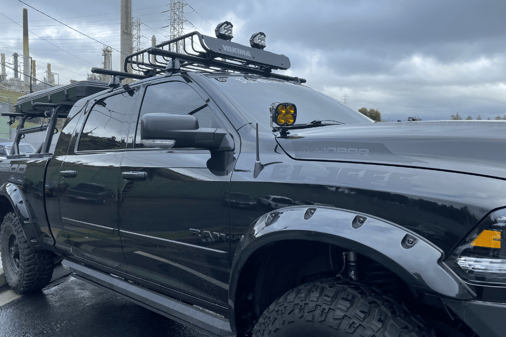 Winter Overlanding Gears, Off-Road and Overlanding Customization in Concord, CA at Outlander Motorsports. Custom black RAM truck equipped with off-road modifications, including roof rack, spotlights, and heavy-duty fender flares.