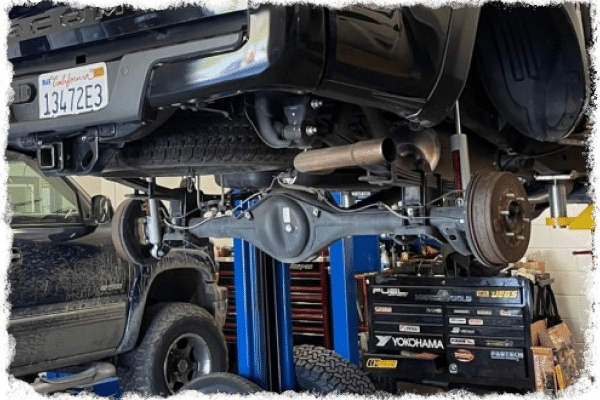 Suspension repair and customization in Martinez & Concord, CA at Outlander Motorsports. Image of black toyota tacoma v6 being lifted for superior suspension repair and customization