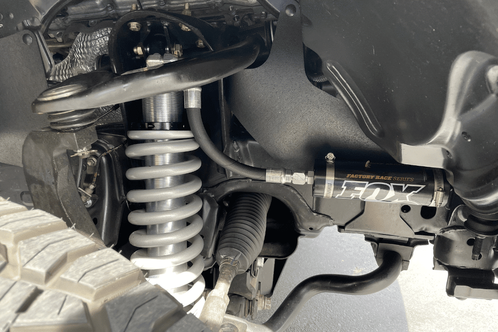 off-road suspension upgrades, Off Road Specialist in Concord, CA at Outlander Motorsports. Close-up of a FOX Factory Race Series shock absorber and coil spring, showcasing a professionally installed lift kit.